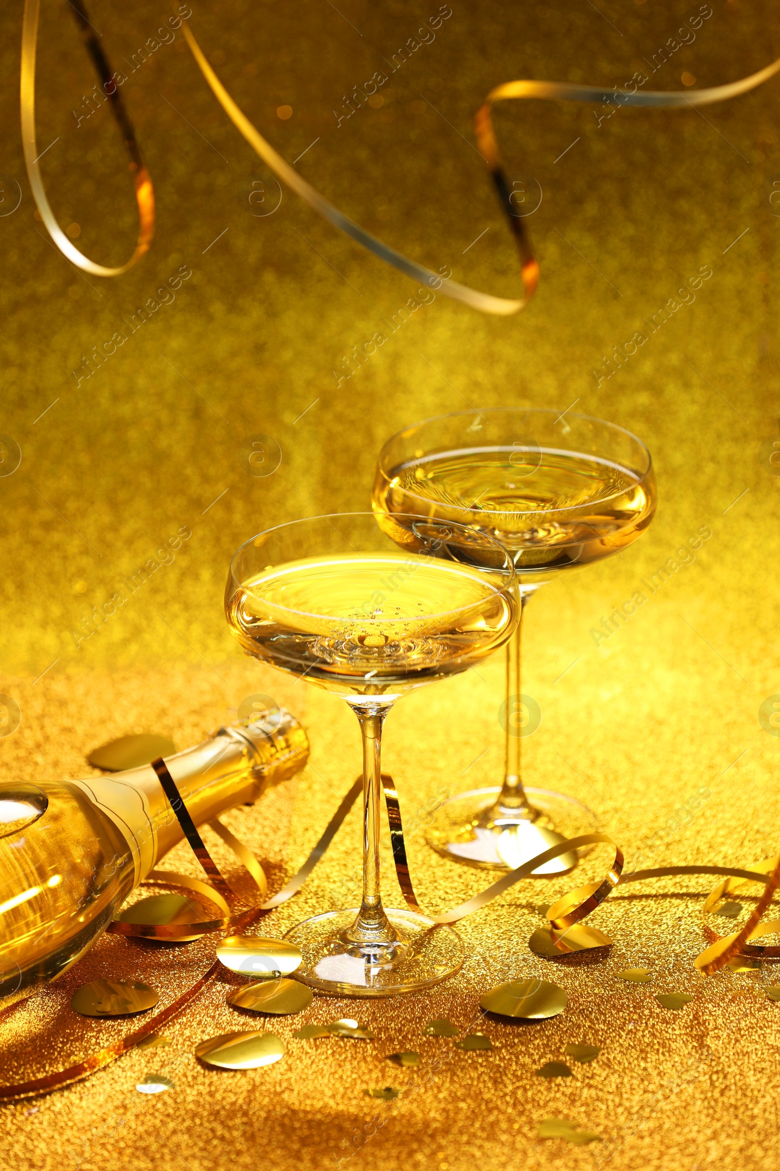 Photo of Champagne, confetti and streamers on golden background