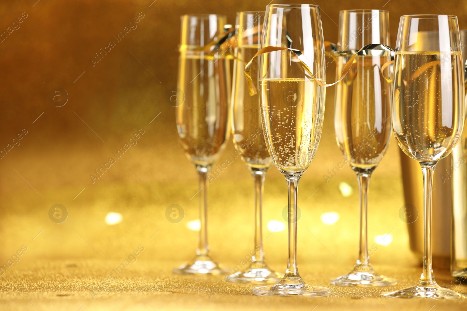 Photo of Champagne in glasses on golden background, closeup. Space for text