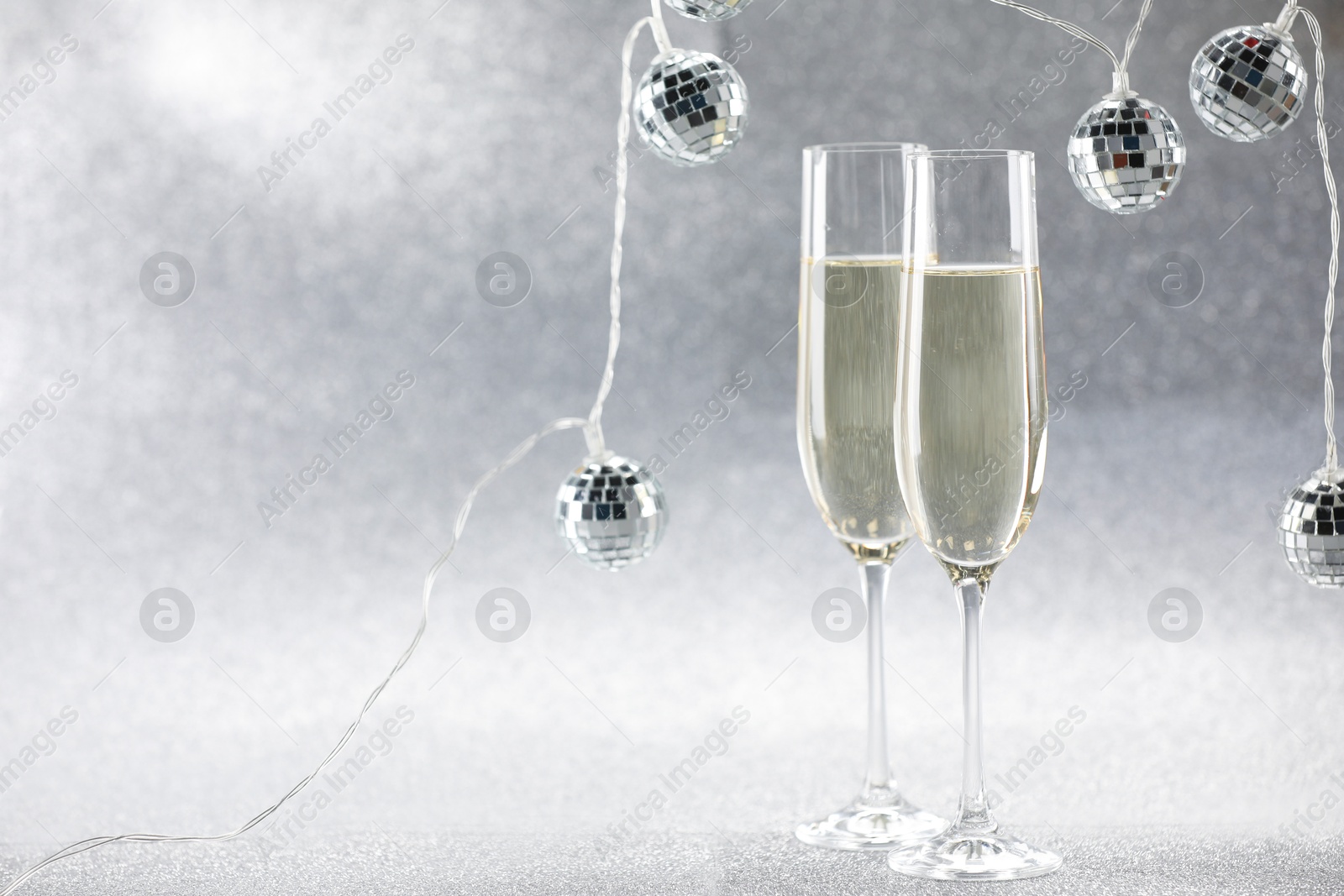 Photo of Champagne in glasses and decor on silver background. Space for text