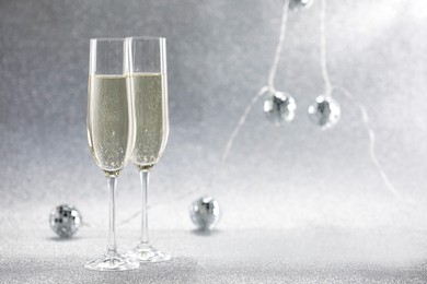 Photo of Champagne in glasses and decor on silver background. Space for text