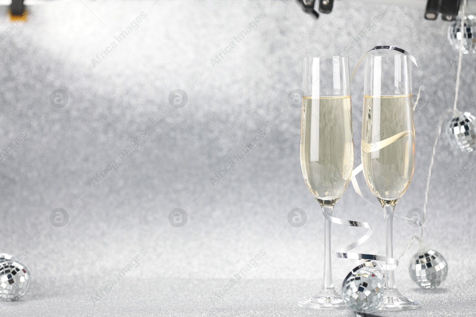 Photo of Champagne in glasses and decor on silver background. Space for text