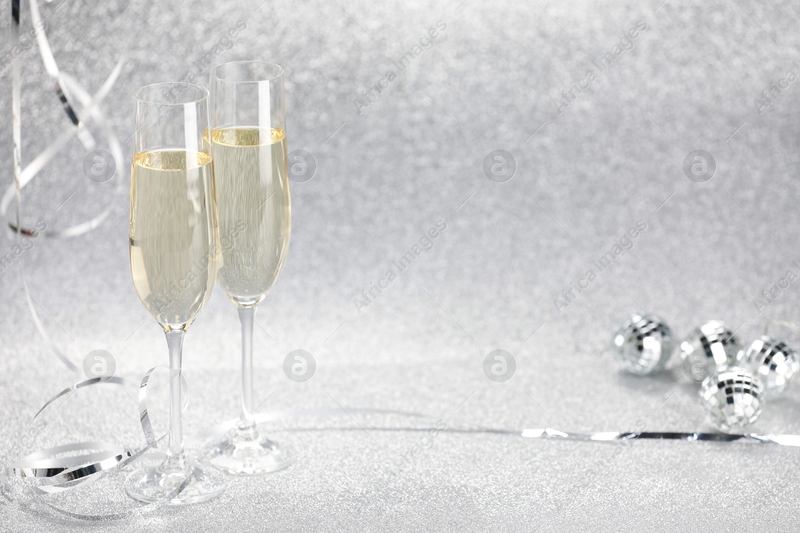 Photo of Champagne in glasses and decor on silver background. Space for text