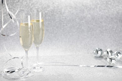 Photo of Champagne in glasses and decor on silver background. Space for text