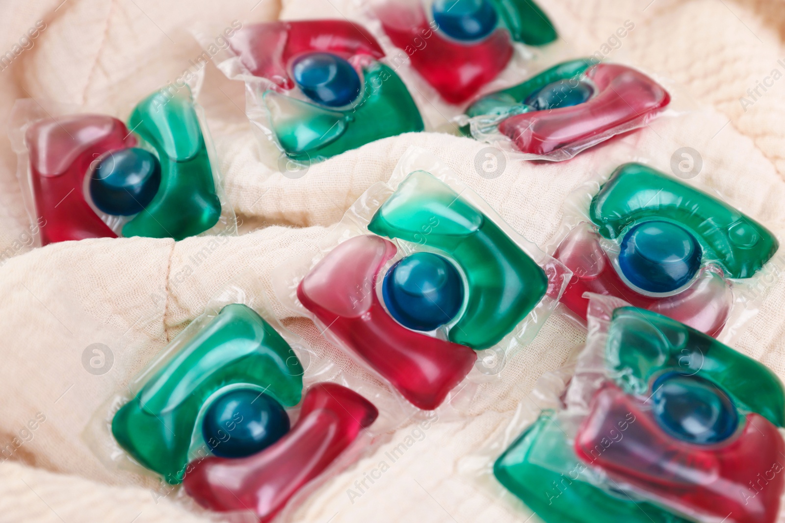 Photo of Laundry detergent capsules on beige fabric, closeup