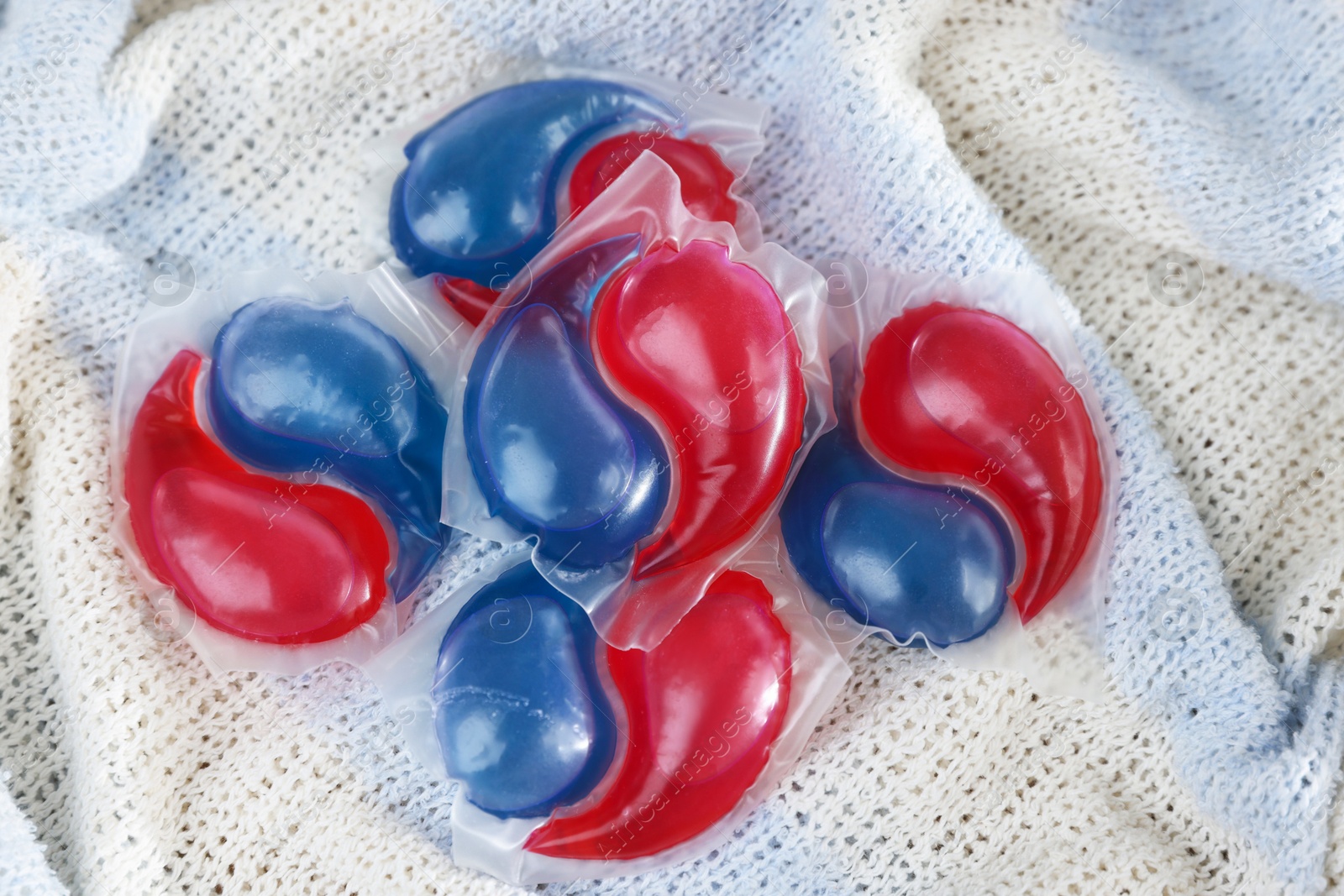 Photo of Laundry detergent capsules on color fabric, closeup