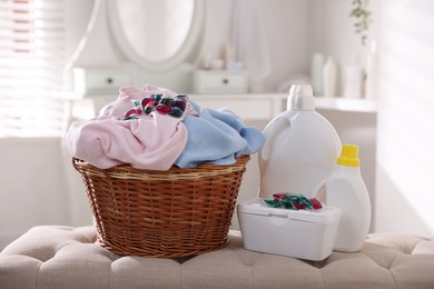 Photo of Laundry capsules, detergents and basket with clothes in bathroom