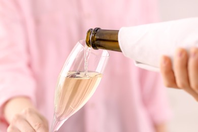 Photo of Waiter pouring champagne into woman's glass, closeup