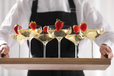 Photo of Waiter holding tray with glasses of champagne indoors, closeup