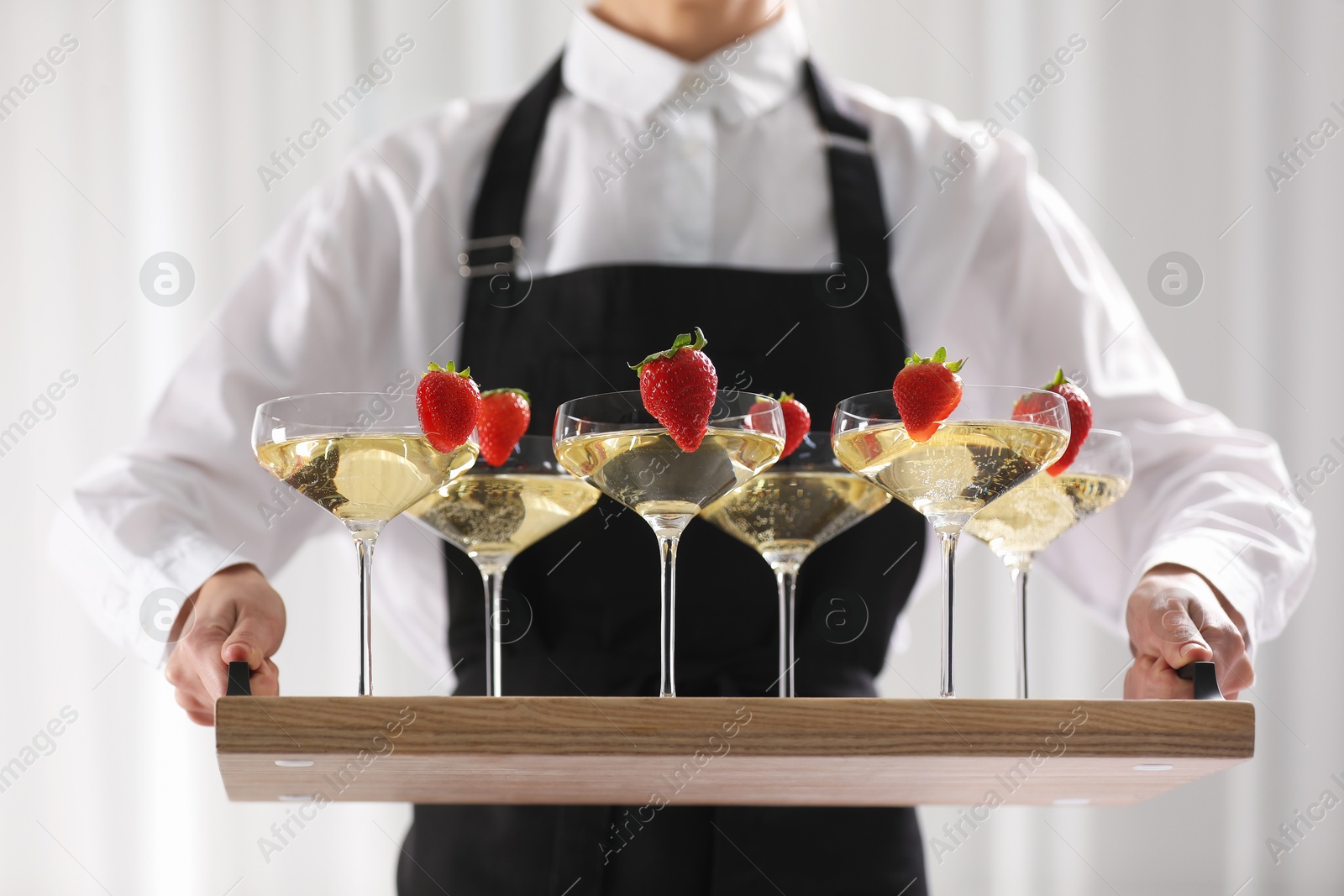 Photo of Waiter holding tray with glasses of champagne indoors, closeup