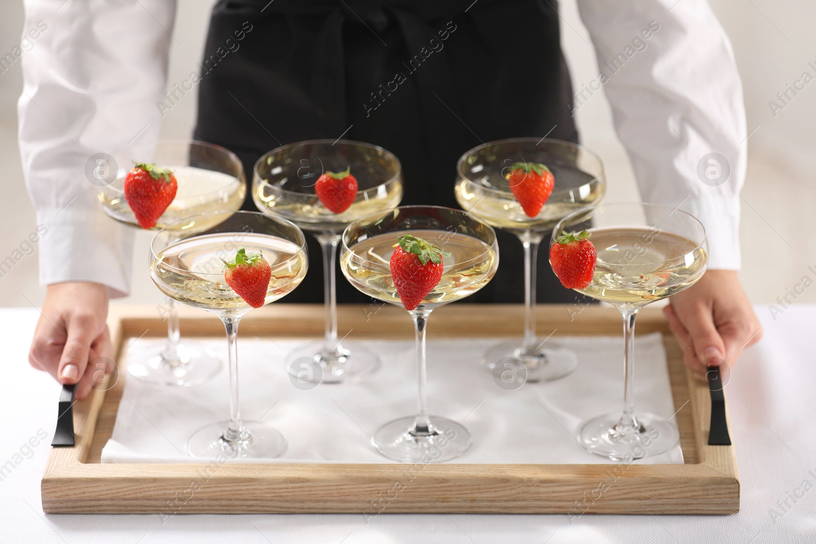 Photo of Waiter holding tray with glasses of champagne indoors, closeup