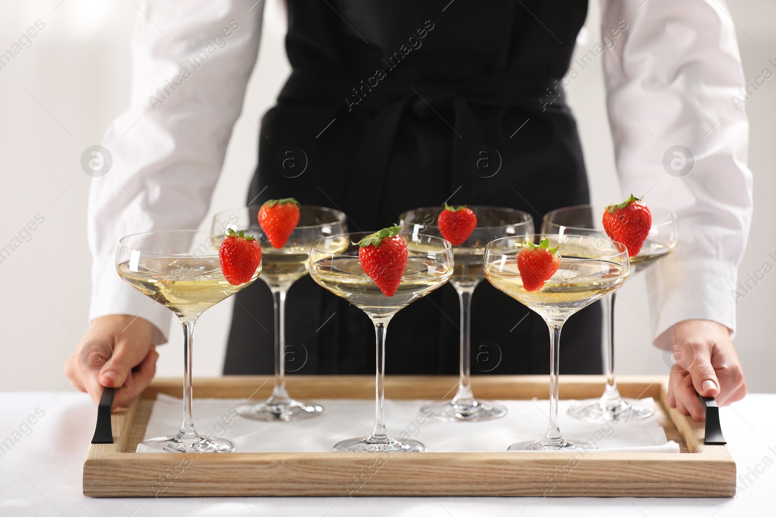 Photo of Waiter holding tray with glasses of champagne indoors, closeup