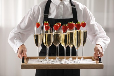 Photo of Waiter holding tray with glasses of champagne indoors, closeup