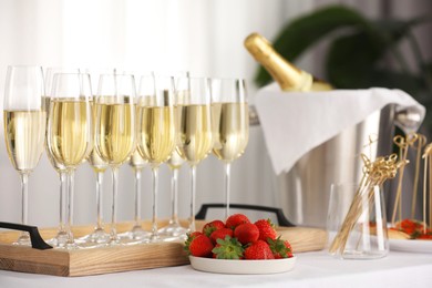 Photo of Champagne in glasses and strawberries on white table indoors