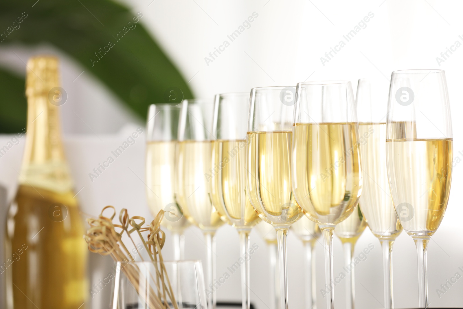 Photo of Champagne in glasses, bottle and skewers indoors, closeup