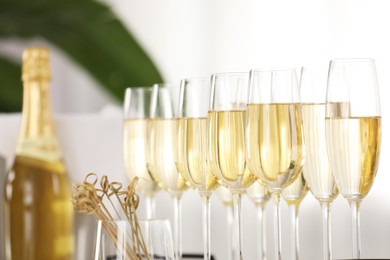 Photo of Champagne in glasses, bottle and skewers indoors, closeup