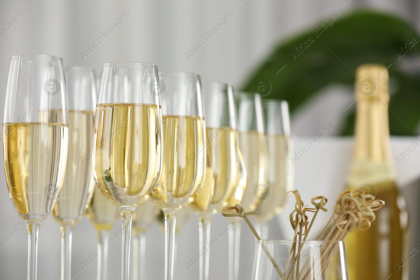 Photo of Champagne in glasses, bottle and skewers indoors, closeup