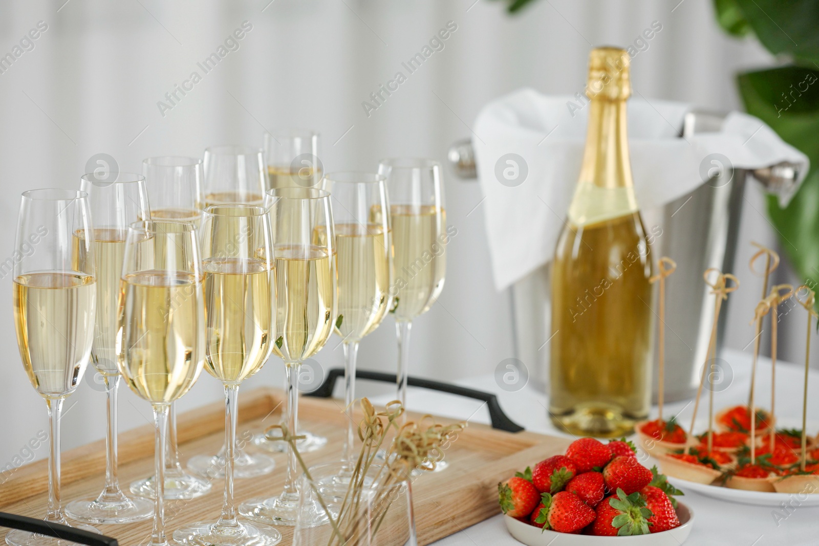 Photo of Champagne, strawberries and canapes with red caviar on white table