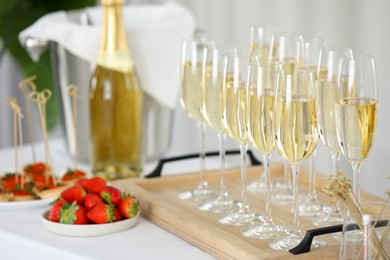 Photo of Champagne, strawberries and canapes on white table