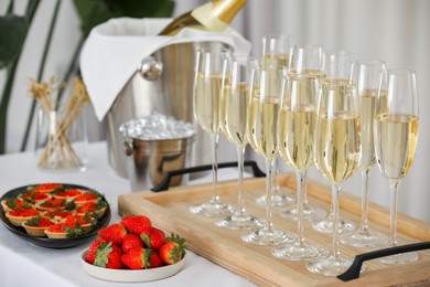 Photo of Champagne, strawberries and canapes with red caviar on white table