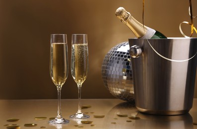 Photo of Champagne in glasses and ice bucket with bottle on golden background