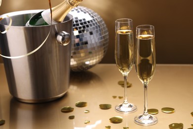 Photo of Champagne in glasses and ice bucket with bottle on golden background