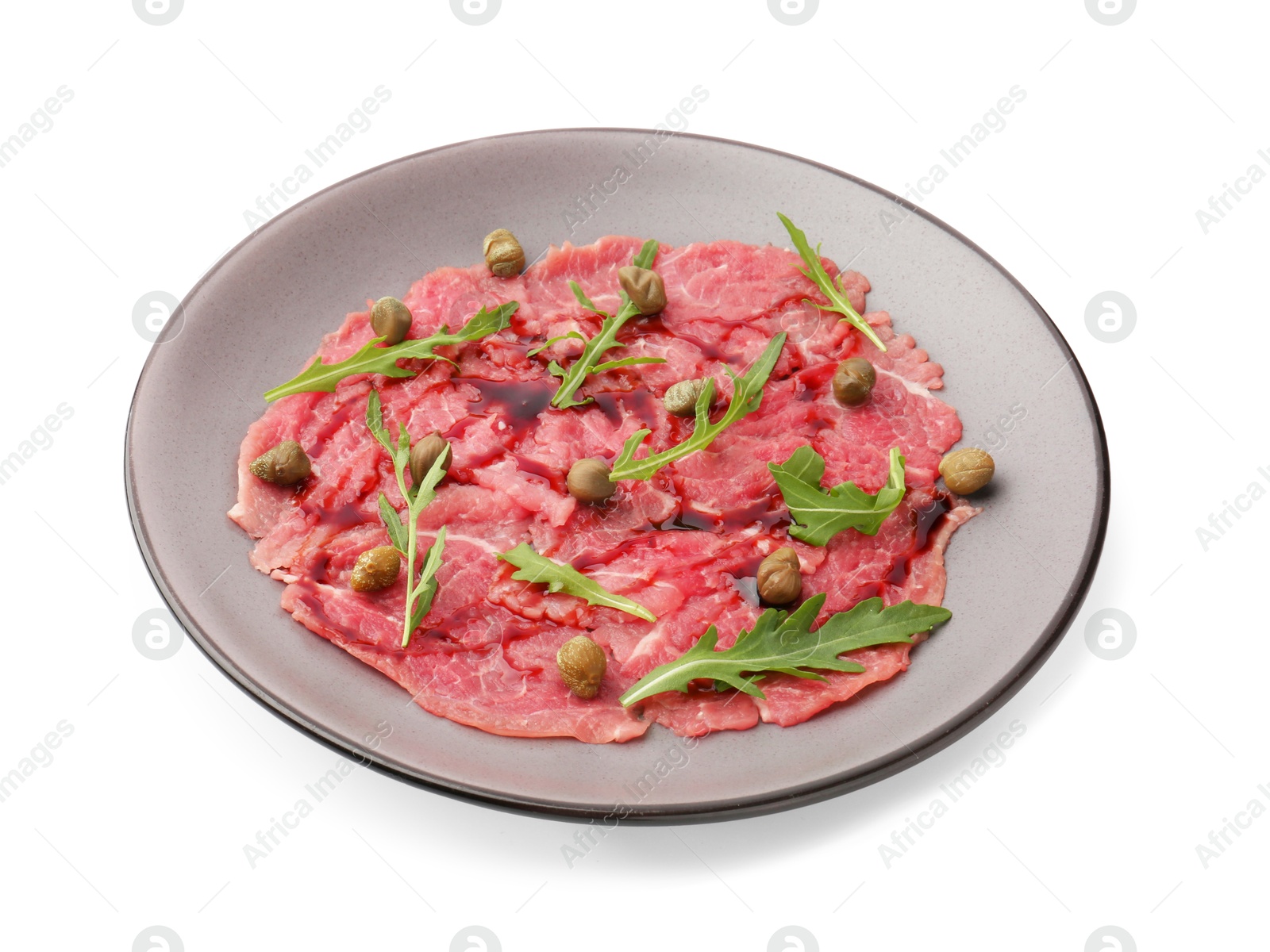 Photo of Fresh beef carpaccio with arugula, capers and sauce isolated on white