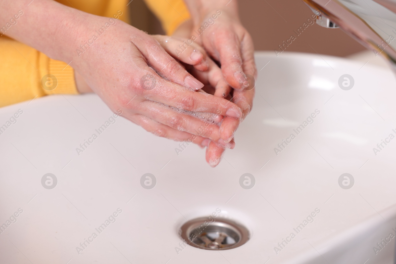 Photo of Mother and daughter washing their hands above sink indoors, closeup