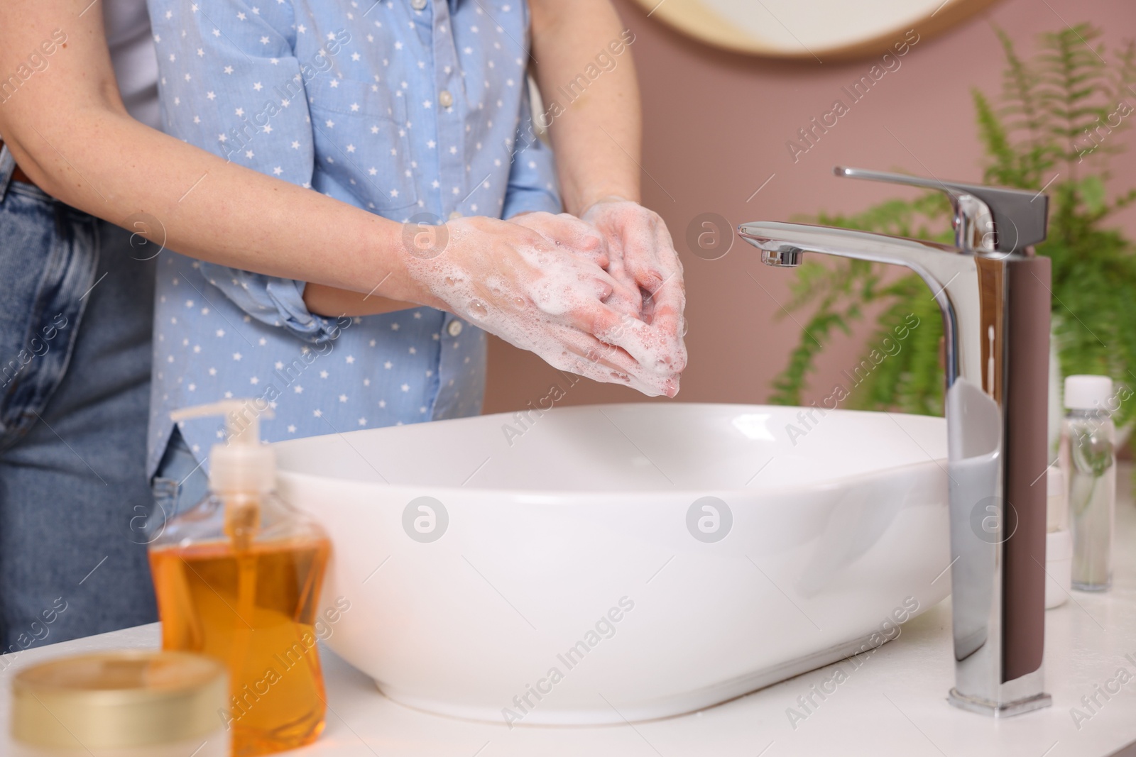 Photo of Mother and daughter washing their hands above sink indoors, closeup