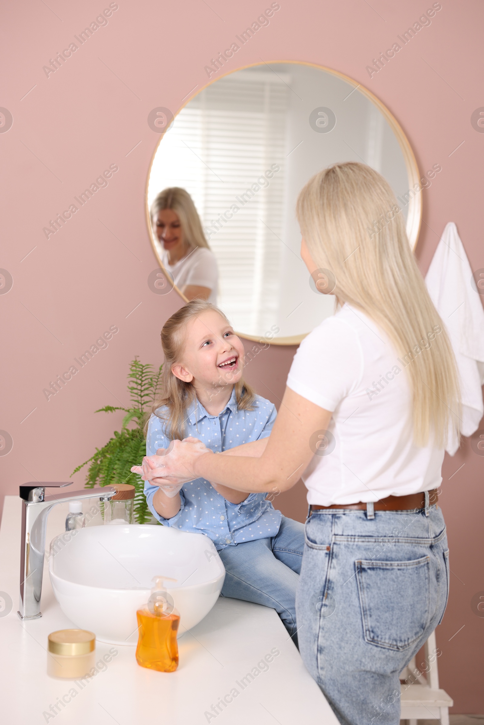 Photo of Happy daughter and her mother washing their hands in bathroom