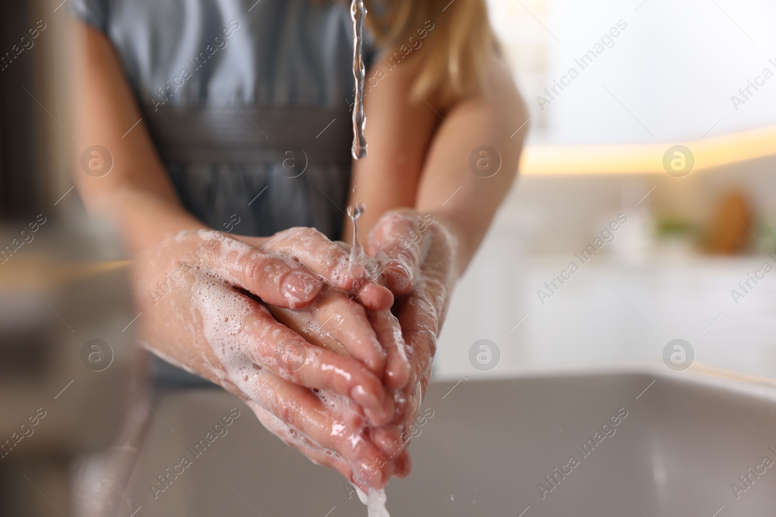 Photo of Mother and daughter washing their hands above sink indoors, closeup. Space for text