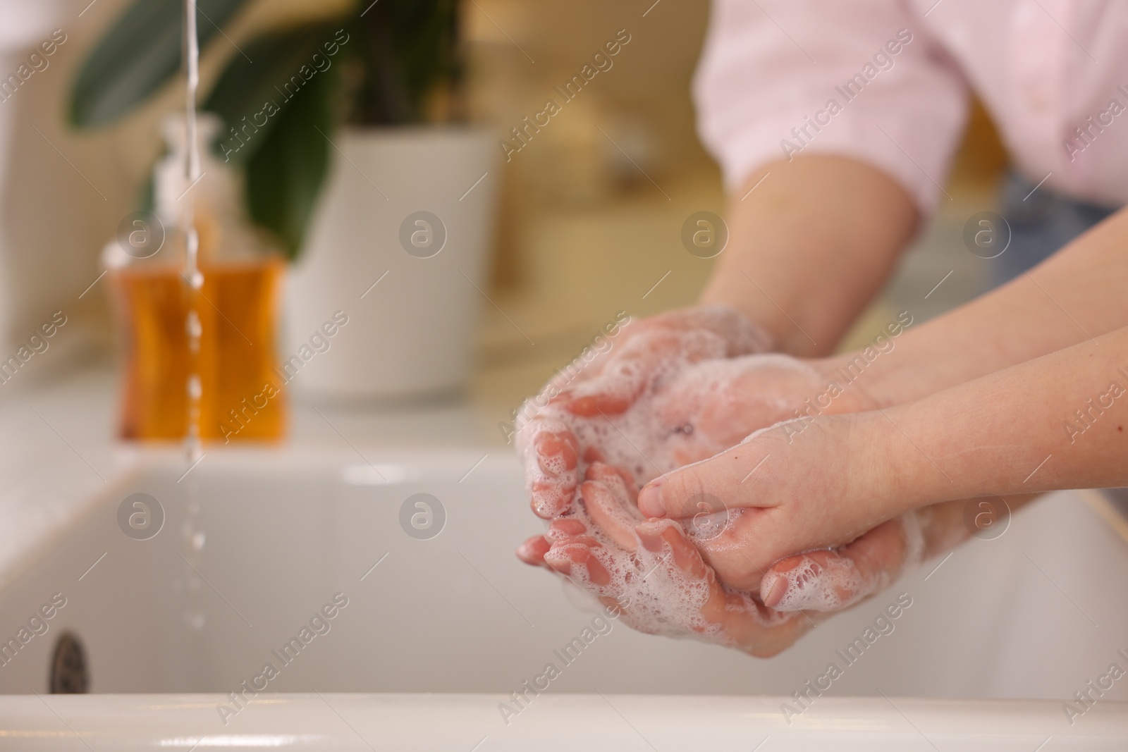 Photo of Mother and daughter washing their hands indoors, closeup. Space for text