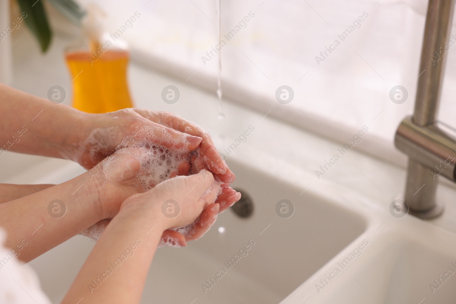 Photo of Mother and daughter washing their hands indoors, closeup. Space for text