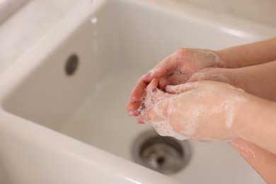 Photo of Mother and daughter washing their hands indoors, closeup. Space for text