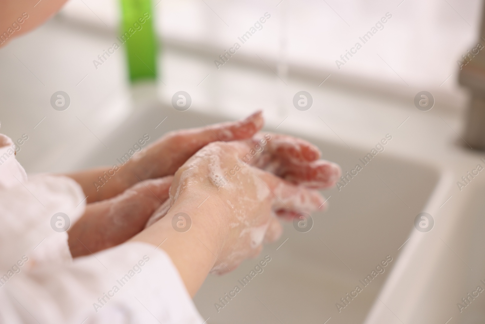 Photo of Mother and daughter washing their hands indoors, closeup. Space for text