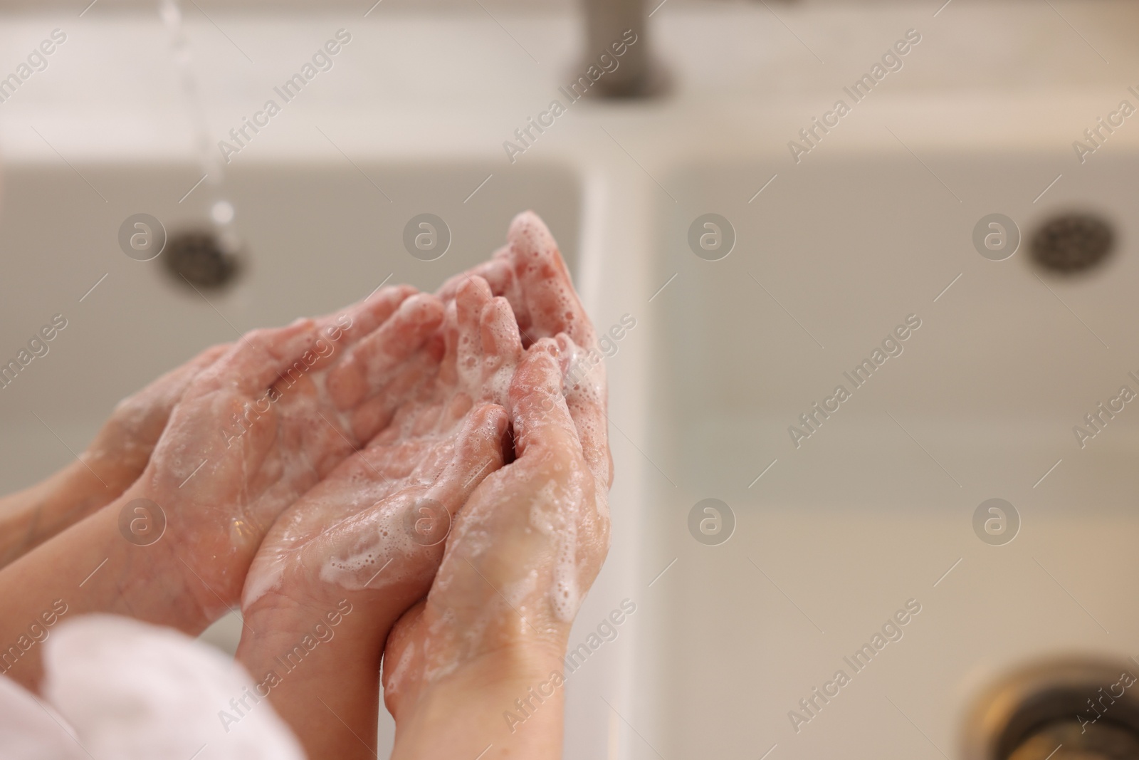 Photo of Mother and daughter washing their hands indoors, closeup. Space for text