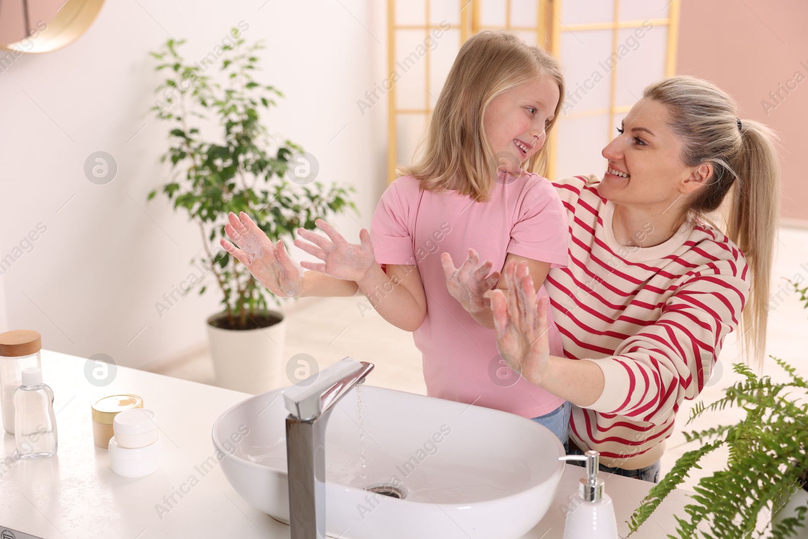 Photo of Happy mother and daughter washing their hands at home