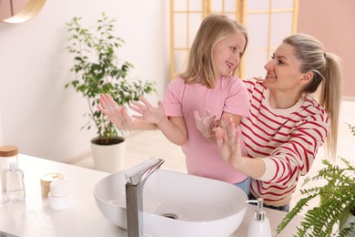 Photo of Happy mother and daughter washing their hands at home