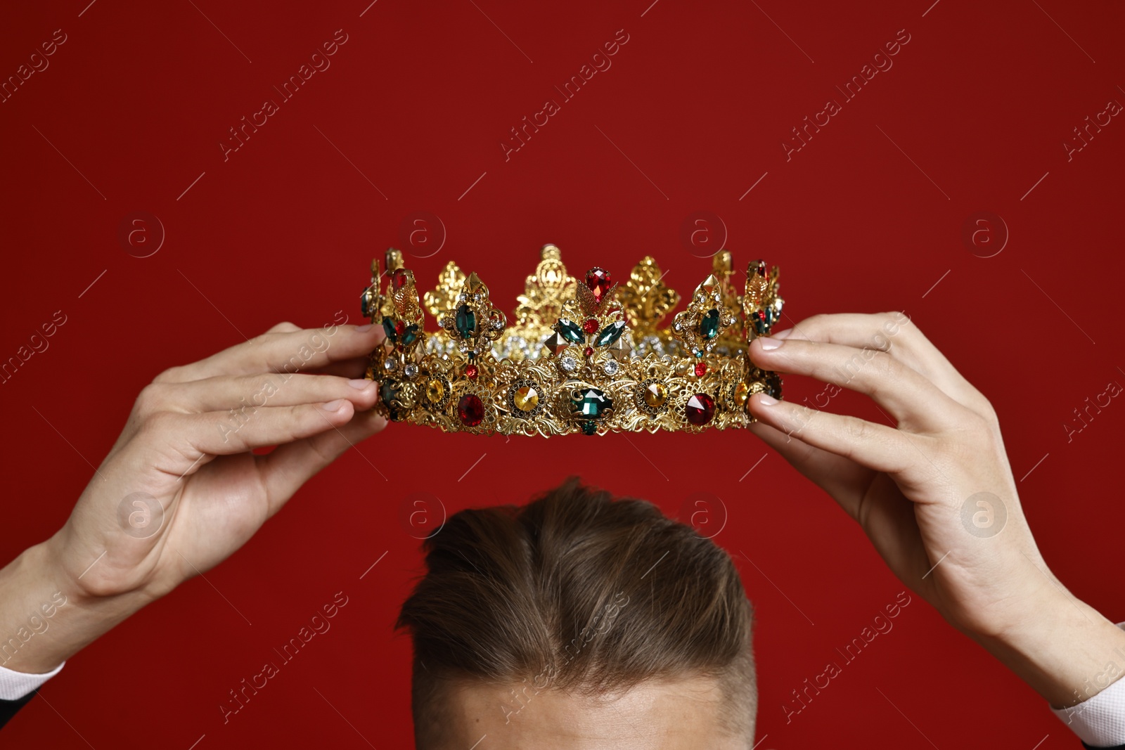 Photo of Man wearing luxury crown on red background, closeup