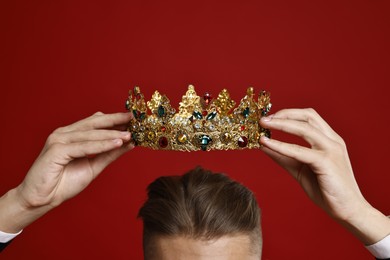 Photo of Man wearing luxury crown on red background, closeup