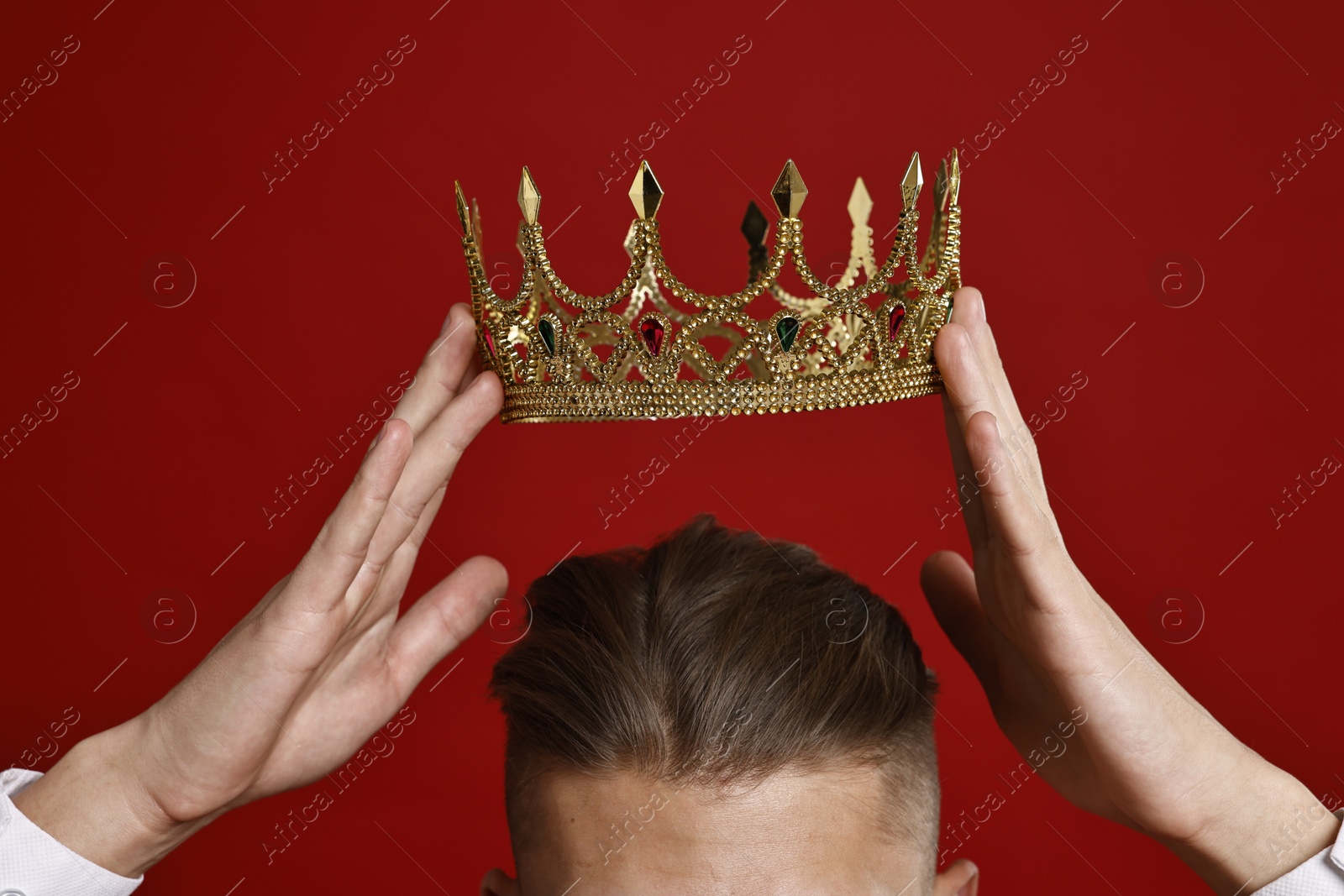 Photo of Man wearing luxury crown on red background, closeup