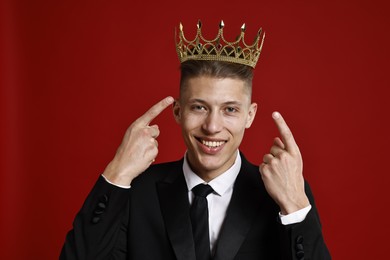 Photo of Handsome man wearing luxury crown on red background