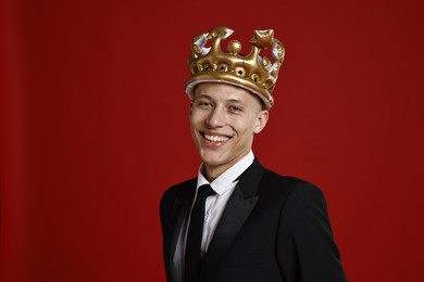 Photo of Handsome man wearing inflatable crown on red background