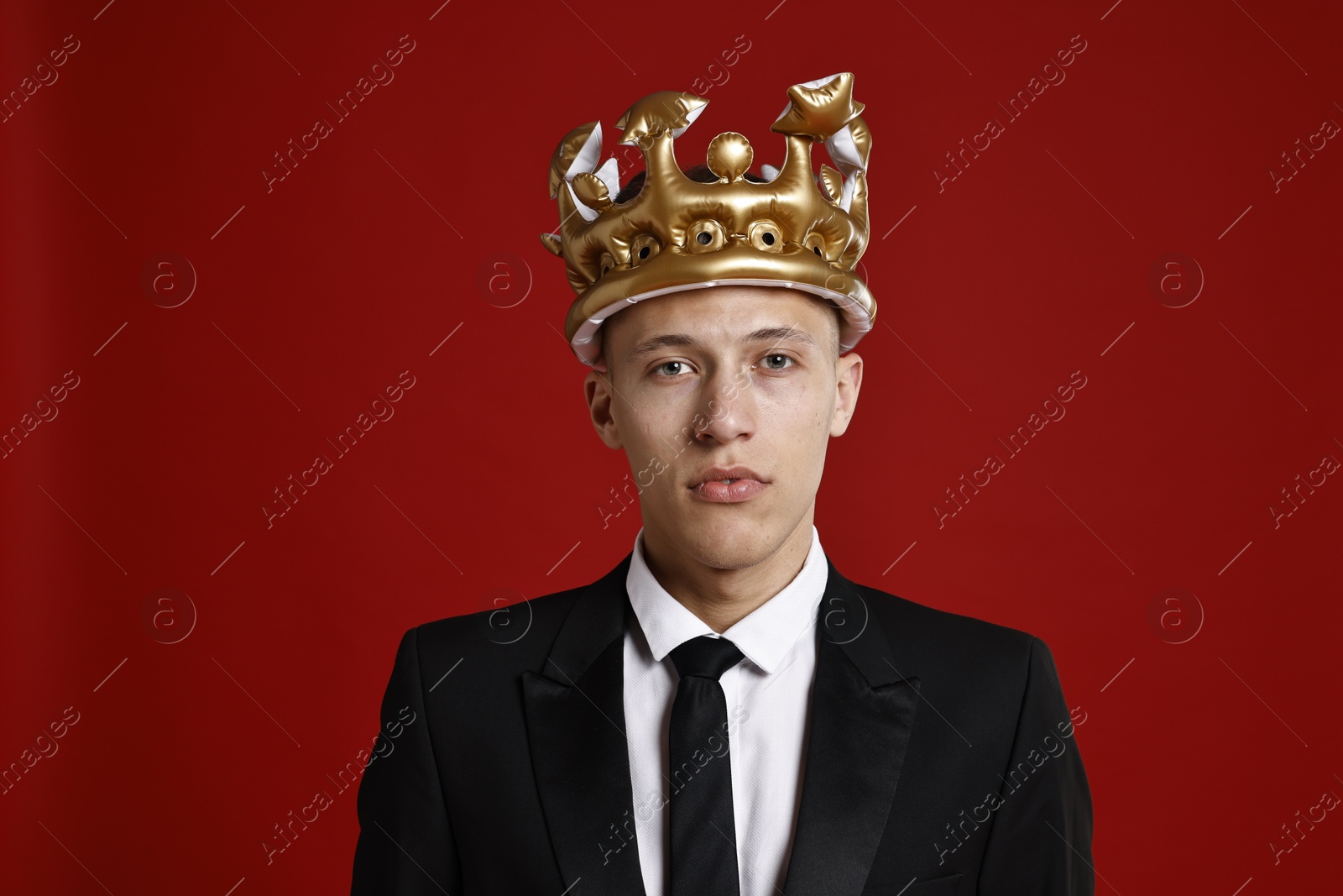 Photo of Handsome man wearing inflatable crown on red background