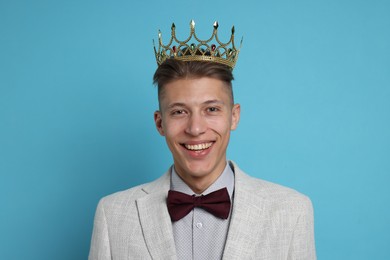 Photo of Handsome man wearing luxury crown on light blue background