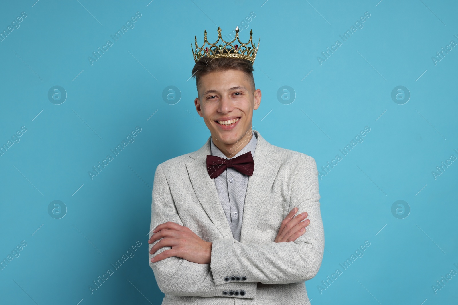 Photo of Handsome man wearing luxury crown on light blue background