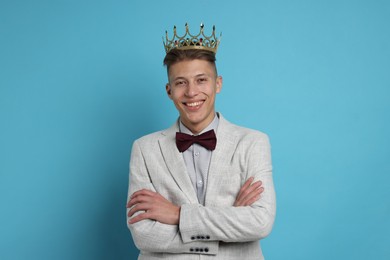 Photo of Handsome man wearing luxury crown on light blue background