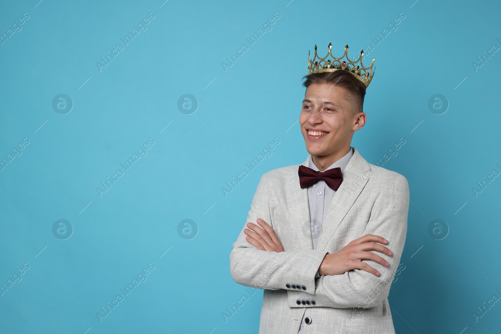 Photo of Handsome man wearing luxury crown on light blue background, space for text