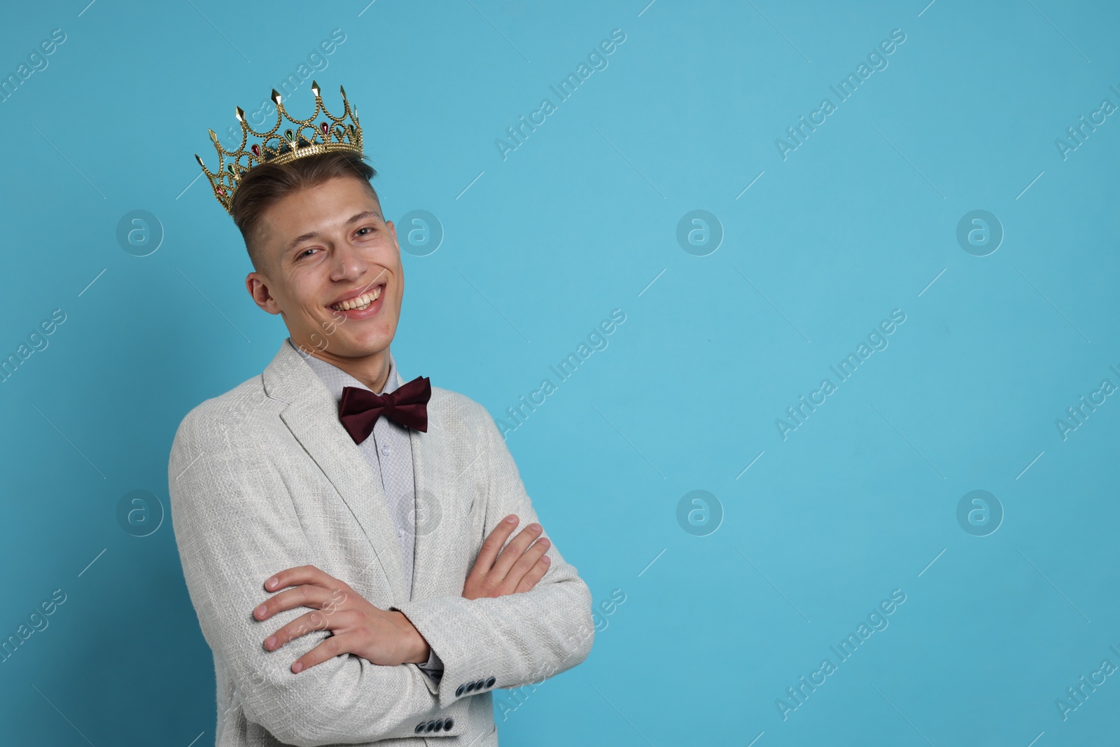 Photo of Handsome man wearing luxury crown on light blue background, space for text