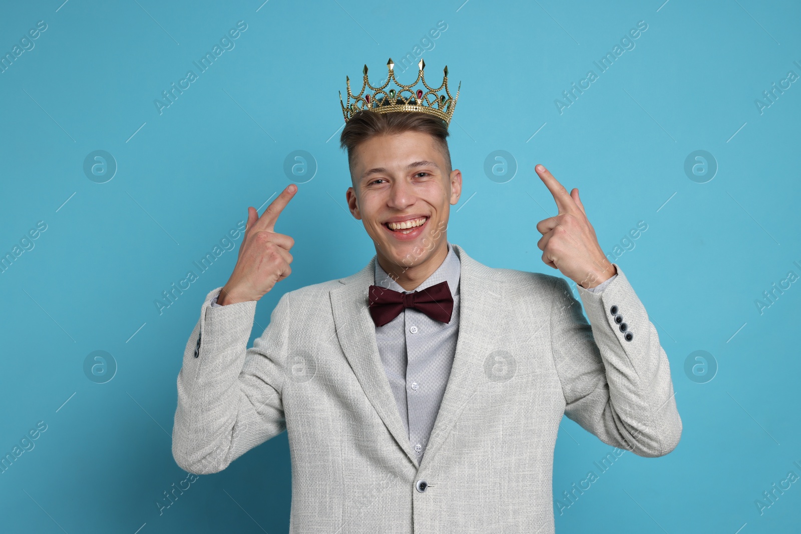 Photo of Handsome man wearing luxury crown on light blue background