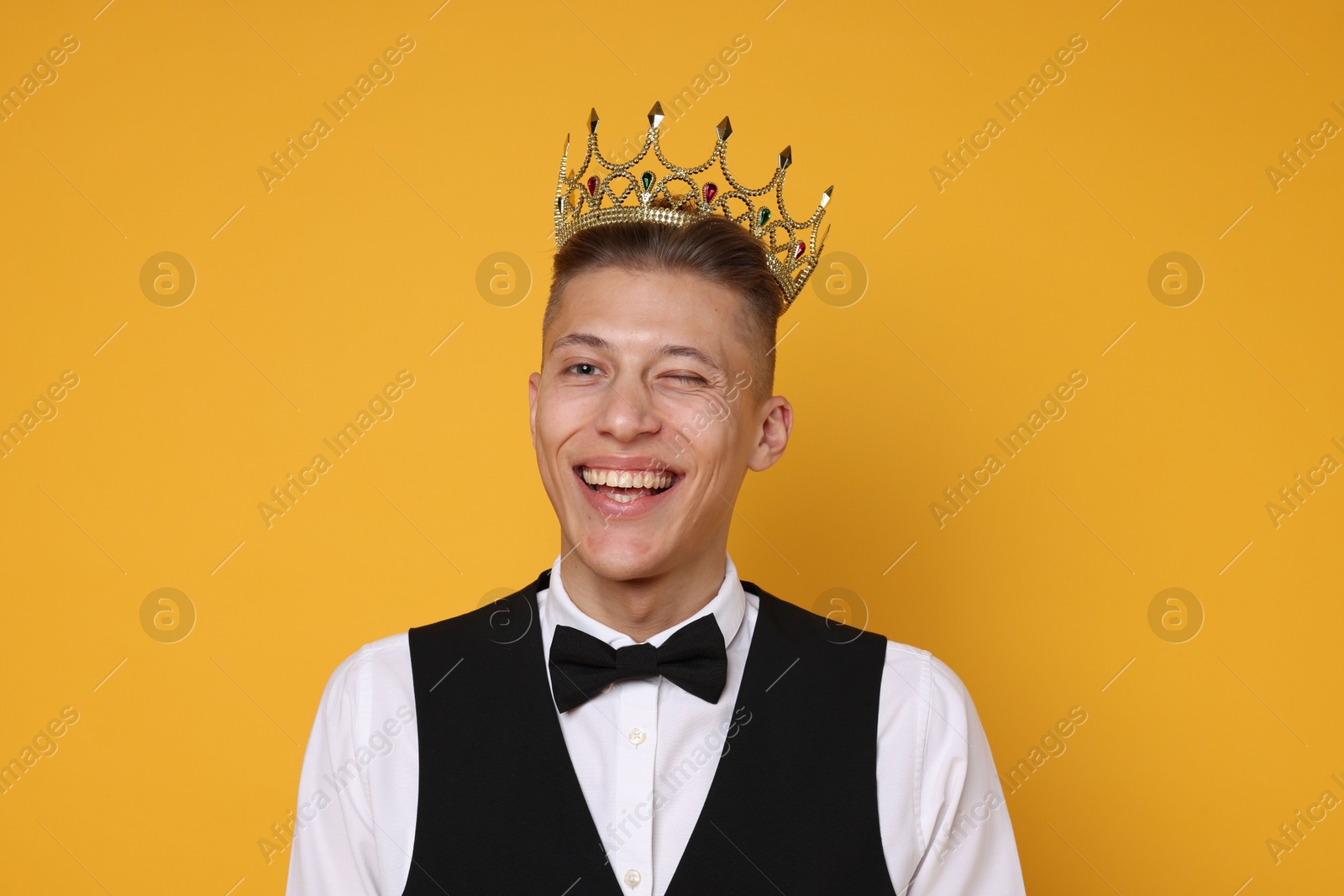 Photo of Handsome man wearing luxury crown on orange background